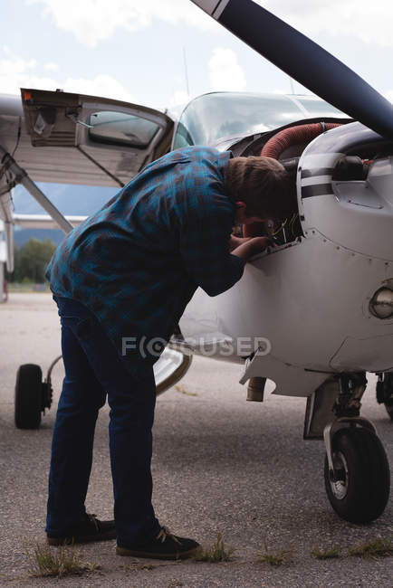 Engineer servicing aircraft engine near hangar on a sunny day — Stock Photo