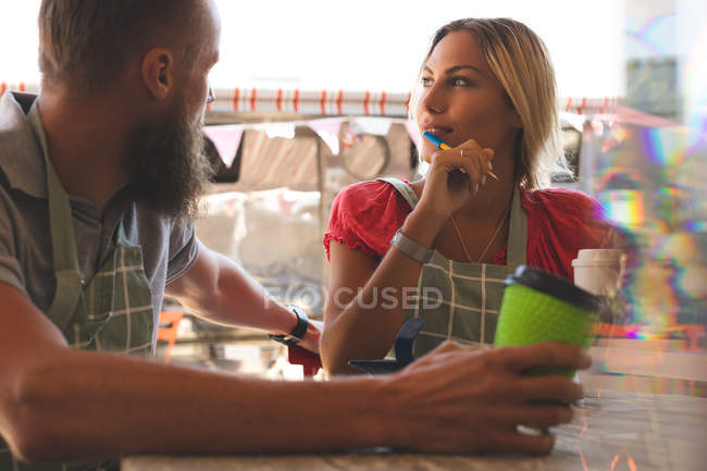 Pareja joven interactuando entre sí en la cafetería al aire libre - foto de stock