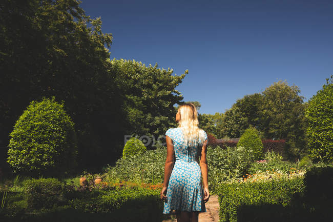 Вид сзади на женщину, стоящую в саду — стоковое фото