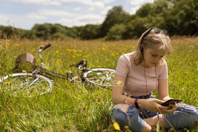 Жінка слухає музику на мобільному телефоні в полі — стокове фото