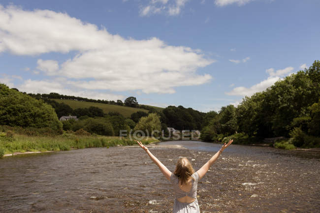 Rear view of woman standing with arms up near stream — Stock Photo