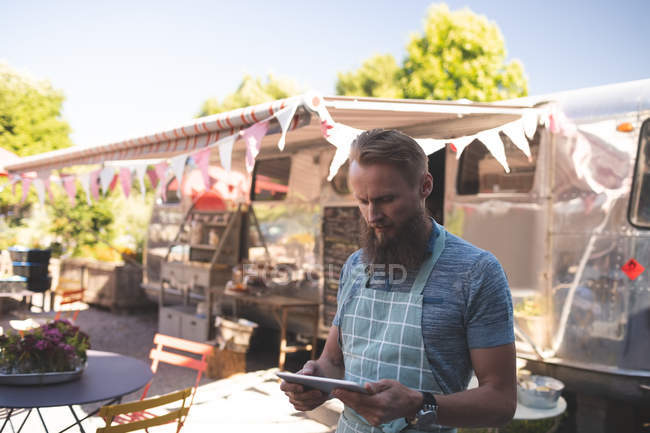 Внимательный мужчина официант, использующий цифровой планшет возле фургона с едой — стоковое фото