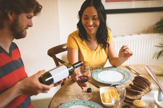 Man serving red wine to woman at home — Stock Photo