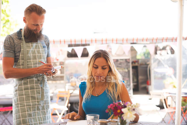 Male waiter taking order in outdoor cafe on a sunny day — Stock Photo