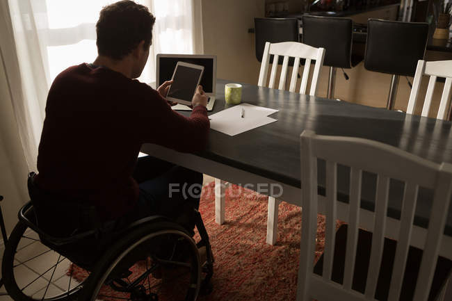 Homme handicapé utilisant une tablette numérique sur la table à manger à la maison — Photo de stock