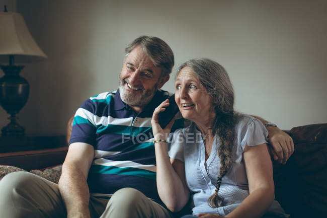 Mujer mayor feliz hablando en el teléfono móvil en casa - foto de stock