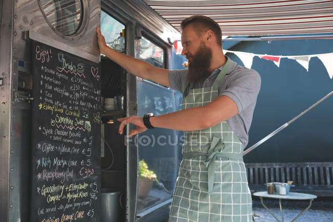 Официант смотрит на доску с меню в фургоне с едой — стоковое фото