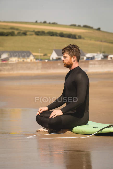 Surfer sitting on surfboard at beach on a sunny day — Stock Photo