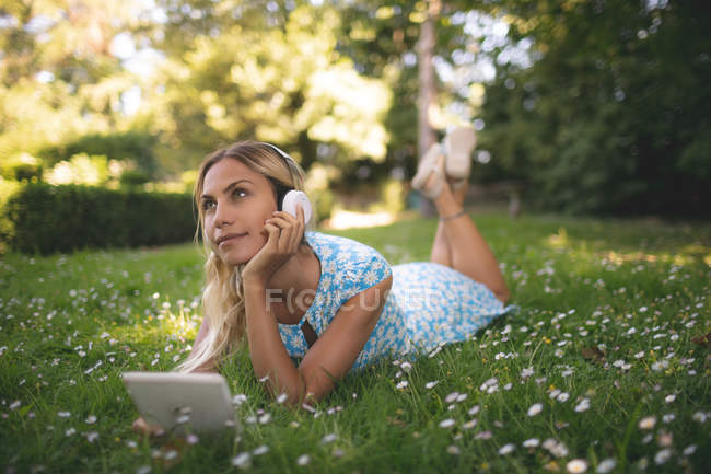 Mujer reflexiva escuchando música en la tableta digital - foto de stock