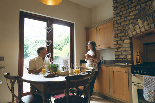 Couple âgé interagissant les uns avec les autres tout en prenant le petit déjeuner à la maison — Photo de stock
