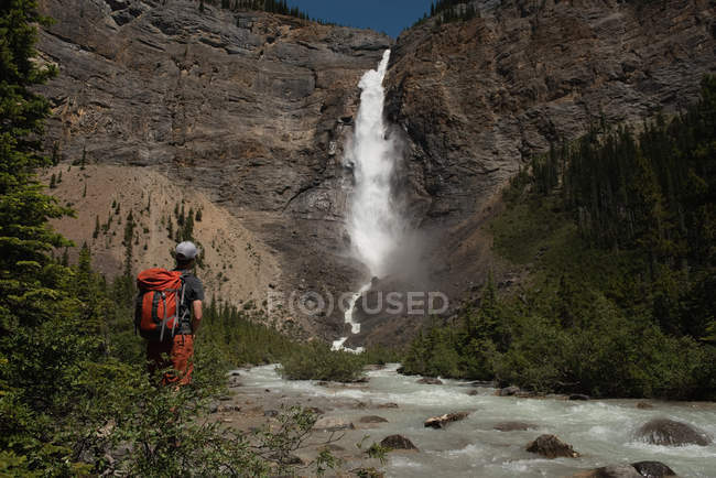 Randonneuse regardant la cascade en montagne — Photo de stock