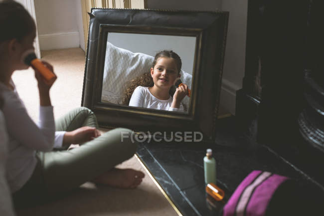 Girl applying makeup in front of mirror at home — Stock Photo