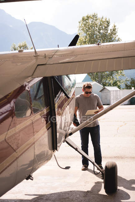 Uomo che utilizza tablet digitale all'hangar in una giornata di sole — Foto stock