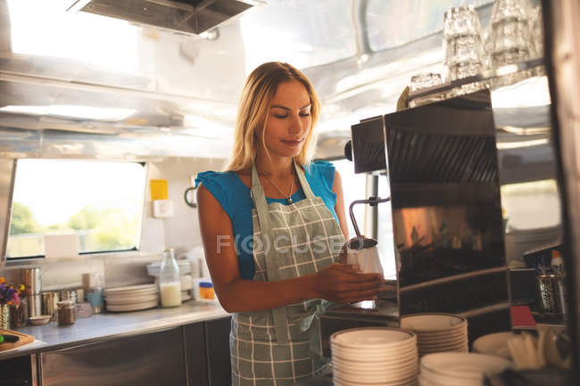Beautiful female waiter preparing coffee in food truck — Stock Photo
