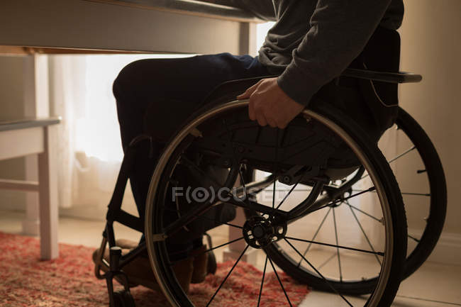 Sección baja del hombre discapacitado en silla de ruedas en casa - foto de stock