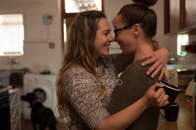 Casal de lésbicas abraçando na cozinha em casa — Fotografia de Stock