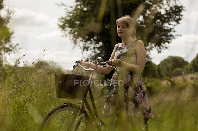 Donna a piedi con la bicicletta nel campo in campagna — Foto stock