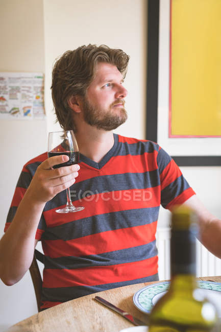 Удумливий чоловік має червоне вино на обідньому столі вдома — стокове фото