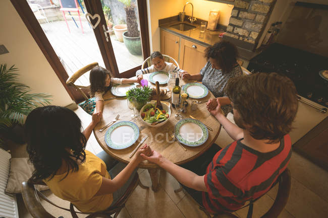 Familia rezando antes de comer en casa - foto de stock