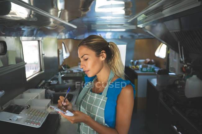 Женщина-официантка пишет заказы на блокнот в фургоне с едой — стоковое фото