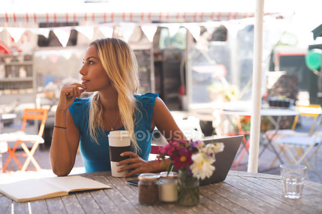 Thoughtful woman having coffee in outdoor cafe — Stock Photo