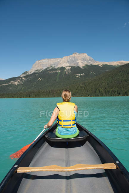 Rückansicht einer Frau, die in einem Fluss in den Bergen Boot fährt — Stockfoto