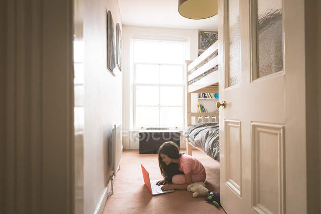 Девочка, использующая ноутбук в спальне дома — стоковое фото