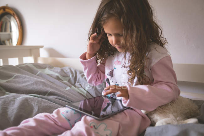 Mädchen benutzt digitales Tablet auf dem Bett im Schlafzimmer zu Hause — Stockfoto