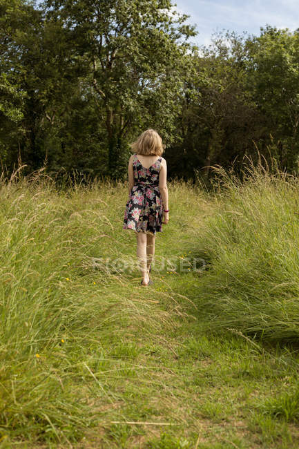 Rückansicht einer Frau, die auf dem Feld geht — Stockfoto
