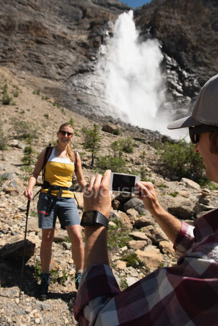 Homme cliquant photo ow femme avec téléphone portable dans les montagnes — Photo de stock
