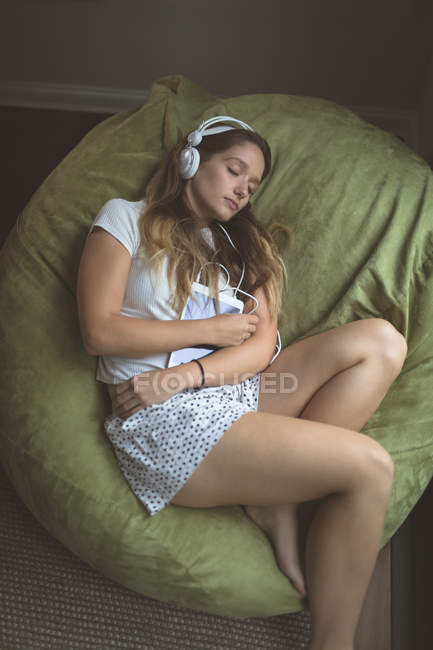 Жінки прослуховування музики на навушники під час сну на дому — стокове фото