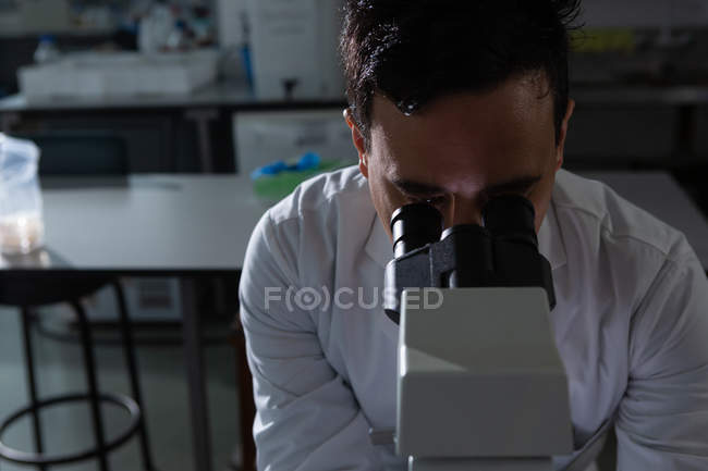 Científico masculino usando microscopio en laboratorio - foto de stock