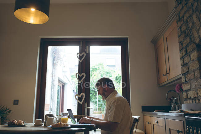 Uomo anziano che utilizza tablet digitale sul tablet da pranzo a casa — Foto stock