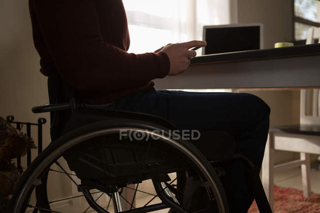 Parte média do homem com deficiência usando telefone celular em casa — Fotografia de Stock