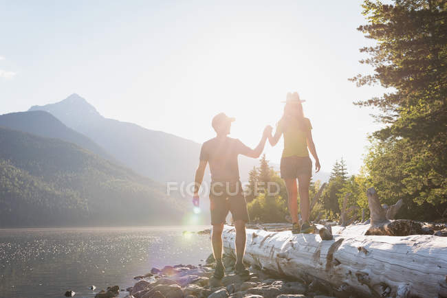 Пара тримає руки біля берега річки в горах — стокове фото