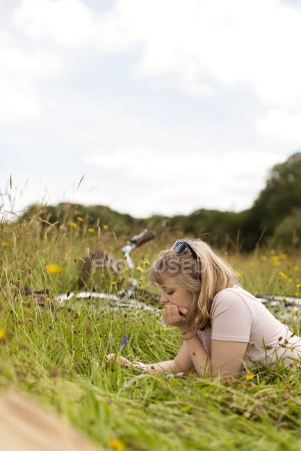 Mulher escrevendo em um bloco de notas no campo — Fotografia de Stock