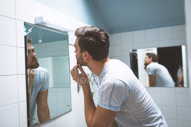 Giovane uomo che si guarda allo specchio a casa — Foto stock