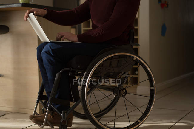 Faible section de l'homme handicapé en utilisant un ordinateur portable à la maison — Photo de stock