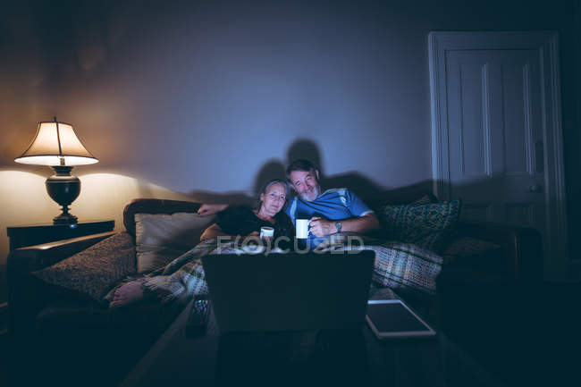 Щаслива старша пара дивиться ноутбук, маючи каву вдома — стокове фото