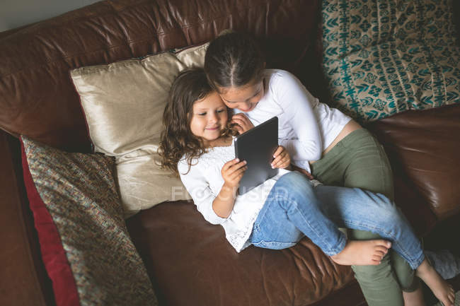 Mädchen nutzen digitales Tablet zu Hause auf dem Sofa — Stockfoto