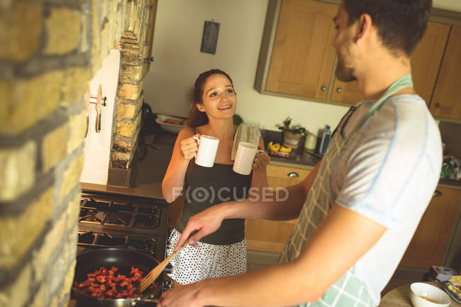 Pareja interactuando entre sí en la cocina en casa - foto de stock