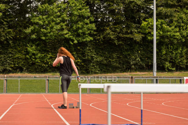 Rear view of female athlete standing on running track — Stock Photo