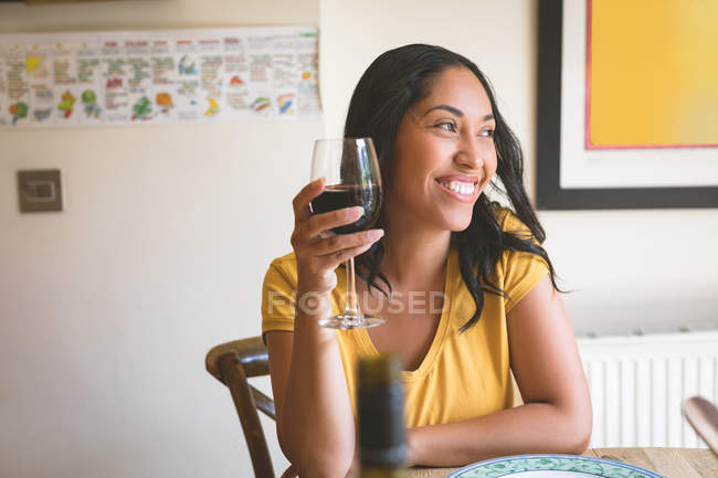 Glückliche Frau mit Rotwein auf dem Esstisch zu Hause — Stockfoto