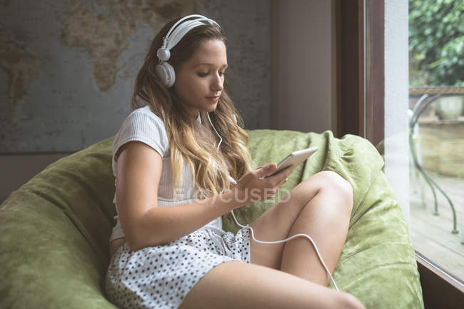 Молода жінка слухає музику на навушниках вдома — стокове фото