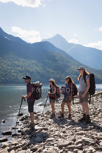 Grupo de excursionistas de pie junto al río en un día soleado - foto de stock