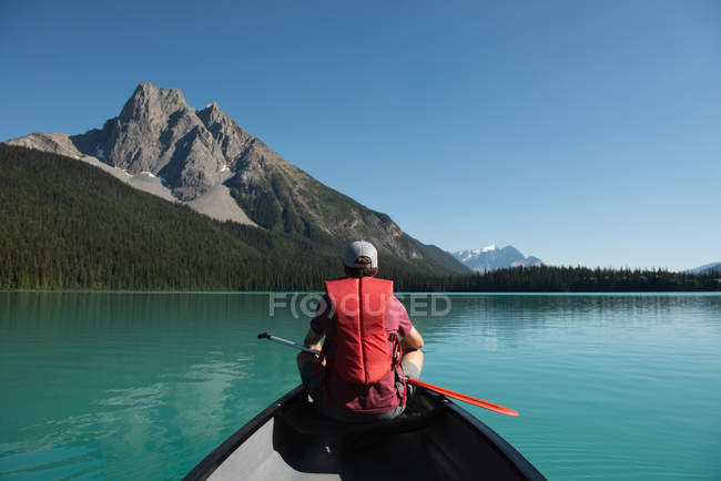 Visão traseira do homem de barco no rio nas montanhas — Fotografia de Stock