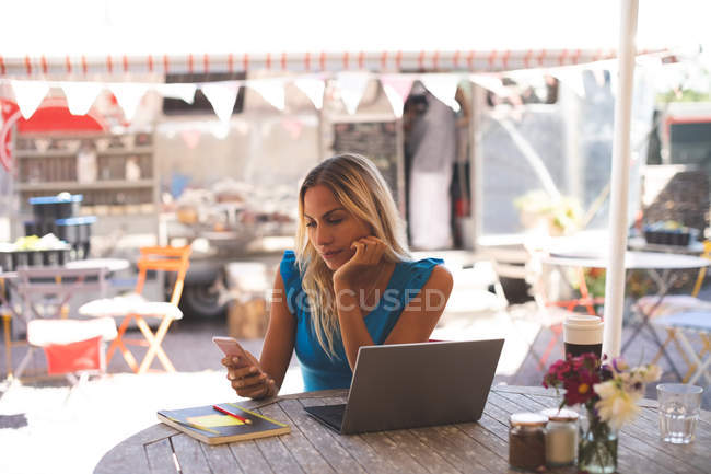 Femme utilisant un ordinateur portable dans un café extérieur — Photo de stock