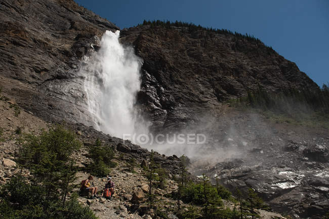 Couple relaxant près d'une cascade en montagne — Photo de stock