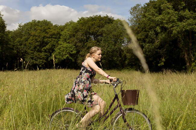 Donna in bicicletta in campo in campagna — Foto stock
