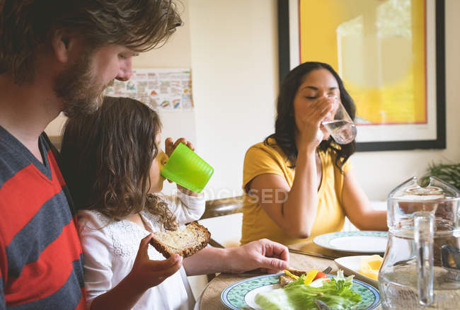 Familia comiendo en la mesa de comedor en casa - foto de stock